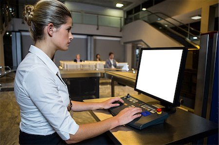 Female staff working on security desk in the airport terminal Stock Photo - Premium Royalty-Free, Code: 6109-08802716