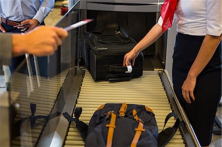 Female staff checking passengers luggage on conveyor belt in airport Photographie de stock - Premium Libres de Droits, Code: 6109-08802863