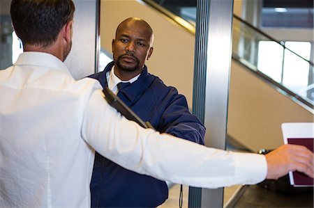 simsearch:6109-08722685,k - Security guard frisking a passenger at airport terminal Stock Photo - Premium Royalty-Free, Code: 6109-08802801