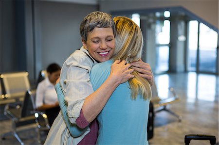 people hugging at airport - Friends embracing each other in the waiting area at airport terminal Stock Photo - Premium Royalty-Free, Code: 6109-08802814