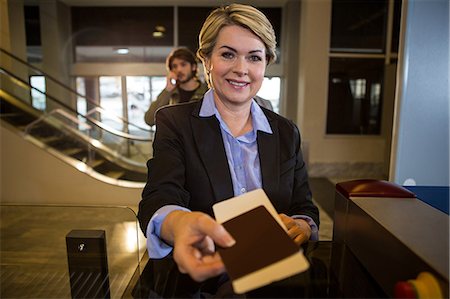 Businesswoman handing over his boarding pass at counter in airport terminal Photographie de stock - Premium Libres de Droits, Code: 6109-08802826