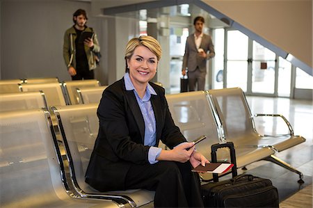simsearch:6109-08929360,k - Businesswoman with passport, boarding pass and luggage sitting in waiting area at airport terminal Photographie de stock - Premium Libres de Droits, Code: 6109-08802836