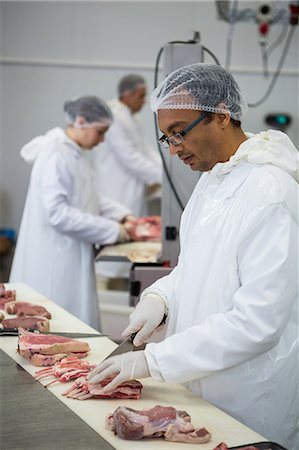 Butcher cutting meat at meat factory Fotografie stock - Premium Royalty-Free, Codice: 6109-08802947