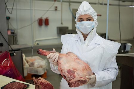 Portrait of female butcher holding meat at meat factory Photographie de stock - Premium Libres de Droits, Code: 6109-08802937