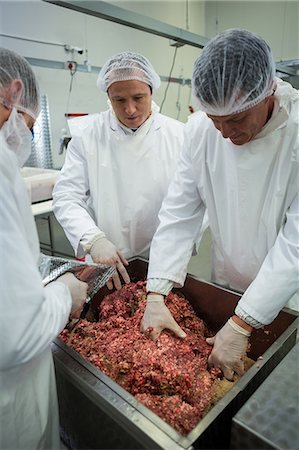 simsearch:6109-08764471,k - Attentive butchers mixing minced meat in meat factory Foto de stock - Sin royalties Premium, Código: 6109-08803007