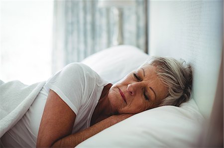 Senior woman resting on bed in bedroom at home Stock Photo - Premium Royalty-Free, Code: 6109-08803140