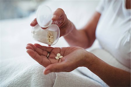 Mid section of senior woman taking medicine in bedroom at home Photographie de stock - Premium Libres de Droits, Code: 6109-08803154