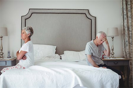 Senior man and woman sitting on bed and ignoring each other in bed room Stock Photo - Premium Royalty-Free, Code: 6109-08803169