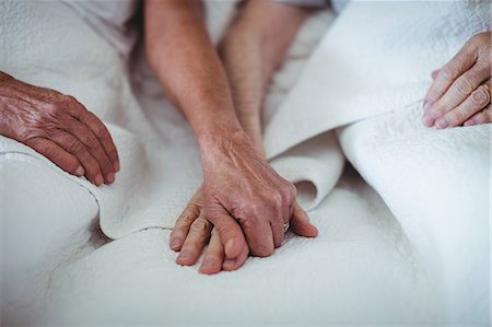 Close-up of senior couple holding hands on bed Stock Photo - Premium Royalty-Free, Code: 6109-08803192