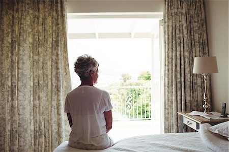 Senior woman sitting on a bed in bedroom at home Photographie de stock - Premium Libres de Droits, Code: 6109-08803105
