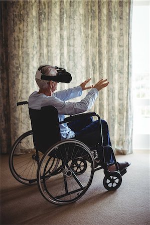 simsearch:6109-08701040,k - Senior man sitting on wheelchair and using virtual reality headset in bedroom at home Foto de stock - Sin royalties Premium, Código: 6109-08803129