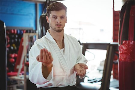 simsearch:6109-08803723,k - Portrait of karate player performing karate stance in fitness studio Foto de stock - Royalty Free Premium, Número: 6109-08803772