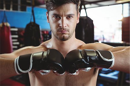 simsearch:6109-08803723,k - Portrait of boxer performing a boxing stance in fitness studio Foto de stock - Royalty Free Premium, Número: 6109-08803704