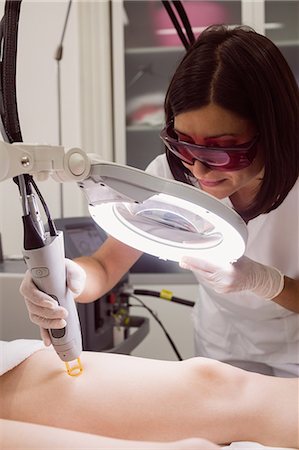 dermatologia - Close up of doctor performing laser hair removal on female patient skin in clinic Fotografie stock - Premium Royalty-Free, Codice: 6109-08803846