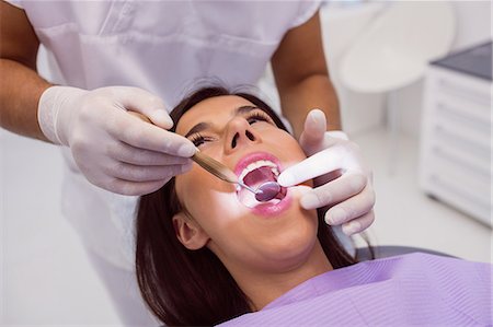 Close up of dentist examining Patient teeth with a mouth mirror Stock Photo - Premium Royalty-Free, Code: 6109-08803869