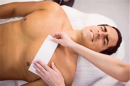 Man getting his chest waxed with wax strip at clinic Photographie de stock - Premium Libres de Droits, Code: 6109-08803831