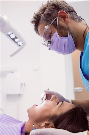simsearch:6109-08700876,k - Dentist examining a female patient with tools at dental clinic 4k Foto de stock - Royalty Free Premium, Número: 6109-08803943
