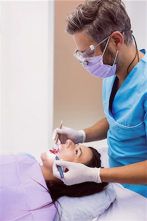 simsearch:6109-08700876,k - Dentist examining a female patient with tools at dental clinic 4k Foto de stock - Royalty Free Premium, Número: 6109-08803940