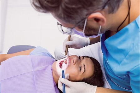 simsearch:6109-08700876,k - Dentist examining a female patient with tools at dental clinic 4k Foto de stock - Royalty Free Premium, Número: 6109-08803941