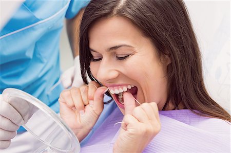 dental bib - Female patient flossing her teeth in dental clinic Stock Photo - Premium Royalty-Free, Code: 6109-08803932