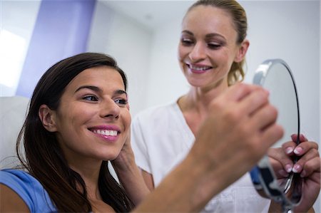 Happy woman checking her skin in the mirror after receiving cosmetic treatment Photographie de stock - Premium Libres de Droits, Code: 6109-08804097