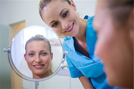 Happy woman checking her skin in the mirror after receiving cosmetic treatment Photographie de stock - Premium Libres de Droits, Code: 6109-08804127