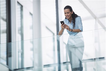 simsearch:6109-08829578,k - Businesswoman using mobile phone inside office building Stock Photo - Premium Royalty-Free, Code: 6109-08804260