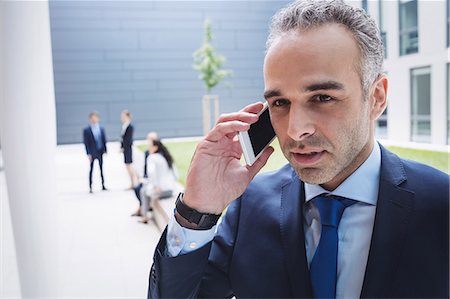 simsearch:6109-08804451,k - Businessman talking on mobile phone outside office building Stockbilder - Premium RF Lizenzfrei, Bildnummer: 6109-08804216