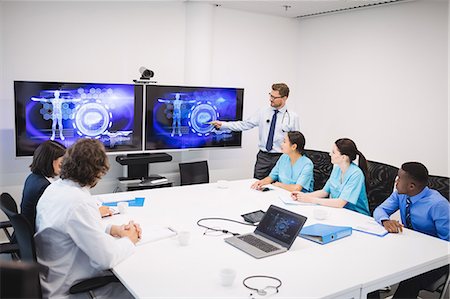 Doctor giving presentation to team of interim doctors at conference room Photographie de stock - Premium Libres de Droits, Code: 6109-08804365