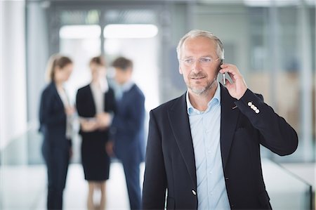 simsearch:6109-08763975,k - Confident businessman talking on mobile phone in office Fotografie stock - Premium Royalty-Free, Codice: 6109-08804320
