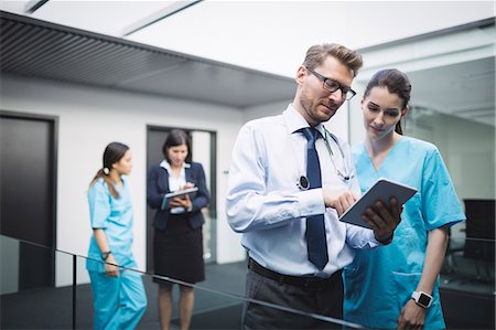 Doctor and nurse discussing over digital tablet in hospital corridor Foto de stock - Sin royalties Premium, Código: 6109-08804401