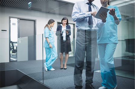 desplazar texto - Doctors and nurses discussing over digital tablet in hospital corridor Foto de stock - Sin royalties Premium, Código: 6109-08804402