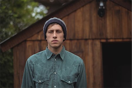 Portrait of man wearing woolly cap standing outside at home brewery Stock Photo - Premium Royalty-Free, Code: 6109-08804528