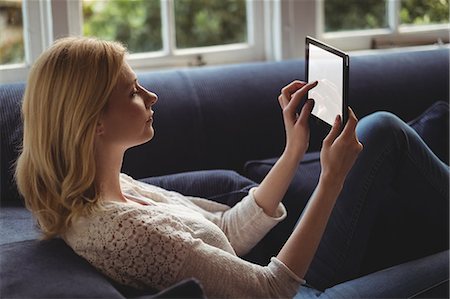 simsearch:6109-08804829,k - Beautiful woman sitting on sofa with digital table in living room at home Stock Photo - Premium Royalty-Free, Code: 6109-08804696