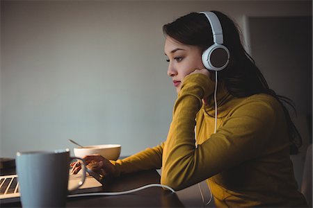 simsearch:6109-08804772,k - Woman listening to headphones while using laptop in study room at home Stockbilder - Premium RF Lizenzfrei, Bildnummer: 6109-08804776