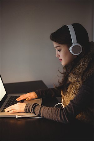 simsearch:6109-08804772,k - Woman listening to headphones while using laptop in study room at home Stockbilder - Premium RF Lizenzfrei, Bildnummer: 6109-08804779