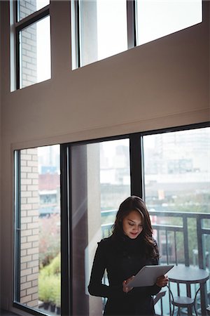 Woman using digital tablet in living room at home Stock Photo - Premium Royalty-Free, Code: 6109-08804787