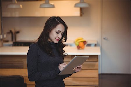 Woman using digital tablet in living room at home Stock Photo - Premium Royalty-Free, Code: 6109-08804784