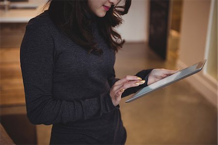 Woman using digital tablet in living room at home Stock Photo - Premium Royalty-Free, Code: 6109-08804786