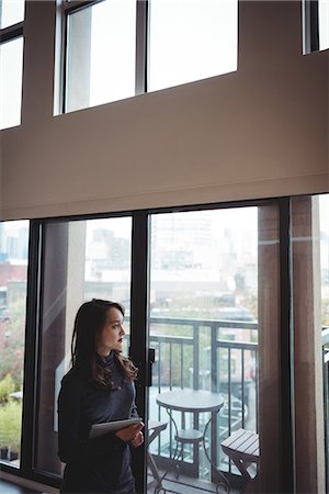 Woman holding digital tablet while looking through the window at home Stock Photo - Premium Royalty-Free, Code: 6109-08804788