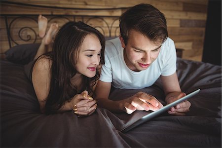 simsearch:6109-08804829,k - Couple lying on bed using digital tablet in bedroom at home Stock Photo - Premium Royalty-Free, Code: 6109-08804840