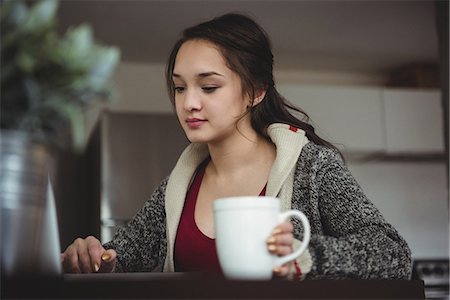 simsearch:6109-08804772,k - Woman having coffee while working on laptop at home Stockbilder - Premium RF Lizenzfrei, Bildnummer: 6109-08804860