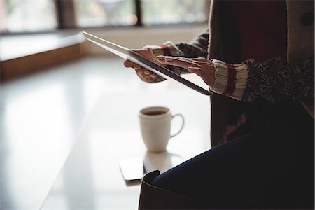 simsearch:6109-08804908,k - Mid section of woman using digital tablet while having coffee at home Photographie de stock - Premium Libres de Droits, Code: 6109-08804866