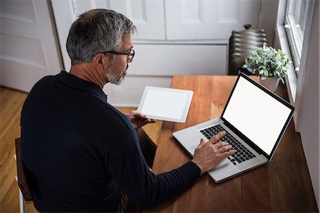 Man using laptop in living room at home Stock Photo - Premium Royalty-Free, Code: 6109-08804881