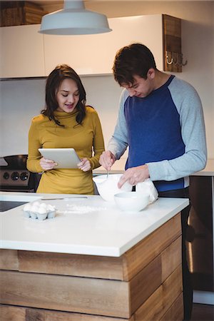 Couple using digital tablet while preparing cookies in kitchen at home Stock Photo - Premium Royalty-Free, Code: 6109-08804810