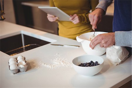 Couple using digital tablet while preparing cookies in kitchen at home Stock Photo - Premium Royalty-Free, Code: 6109-08804812