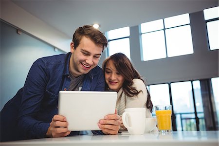 daily routine - Couple using digital tablet while having breakfast at home Stock Photo - Premium Royalty-Free, Code: 6109-08804828