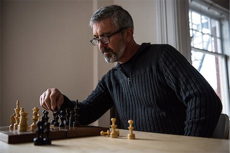 Attentive man playing chess at home Stock Photo - Premium Royalty-Free, Code: 6109-08804969