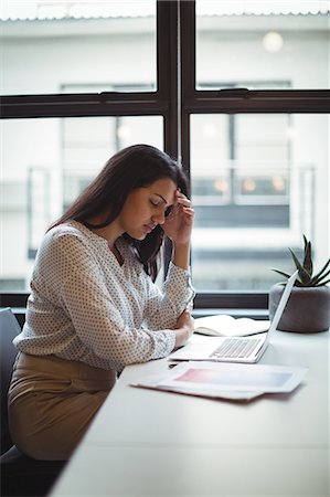 simsearch:6109-08701307,k - Stressed businesswoman sitting at his desk in office Foto de stock - Sin royalties Premium, Código: 6109-08805081