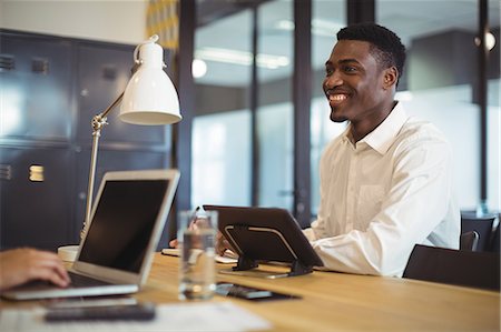 simsearch:6109-08805110,k - Businessman and a colleague working at their desk in office Photographie de stock - Premium Libres de Droits, Code: 6109-08805099